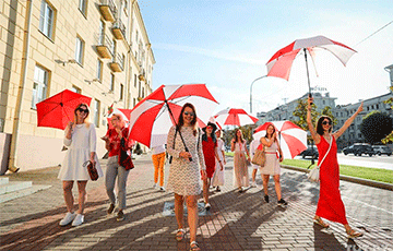 Девушки с бело-красно-белыми зонтиками гуляют по проспекту Независимости