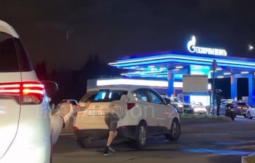 Двое россиян толкают машину в очереди на АЗС, надеясь приобрести топливо